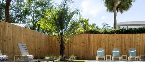 Una piscina con sillas de descanso y una valla de madera.