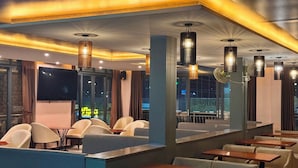 Interior de restaurante con cabinas, mesas y lámparas colgantes.