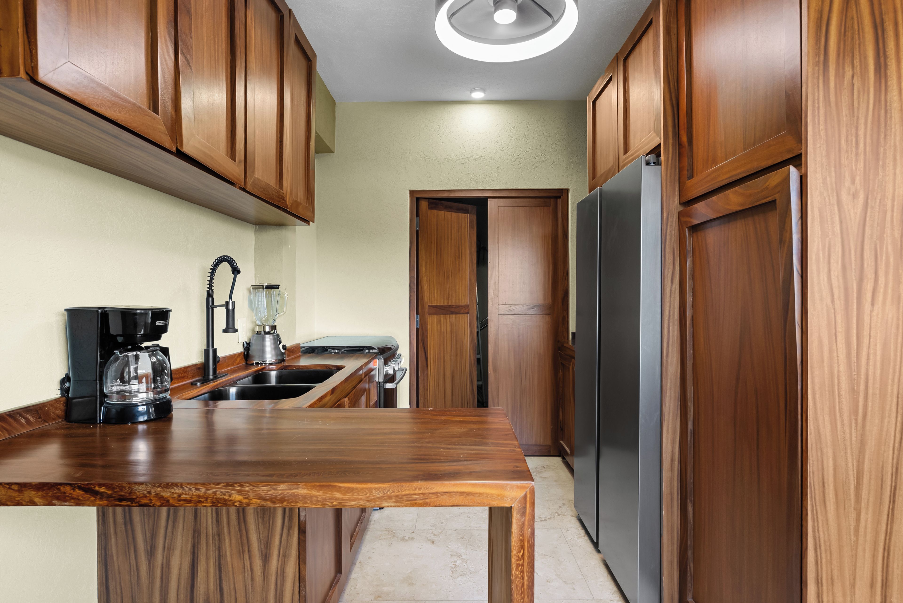 Una cocina con armarios de madera, un refrigerador de acero inoxidable, una cafetera y una licuadora.