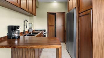 Una cocina con armarios de madera, un refrigerador de acero inoxidable, una cafetera y una licuadora.