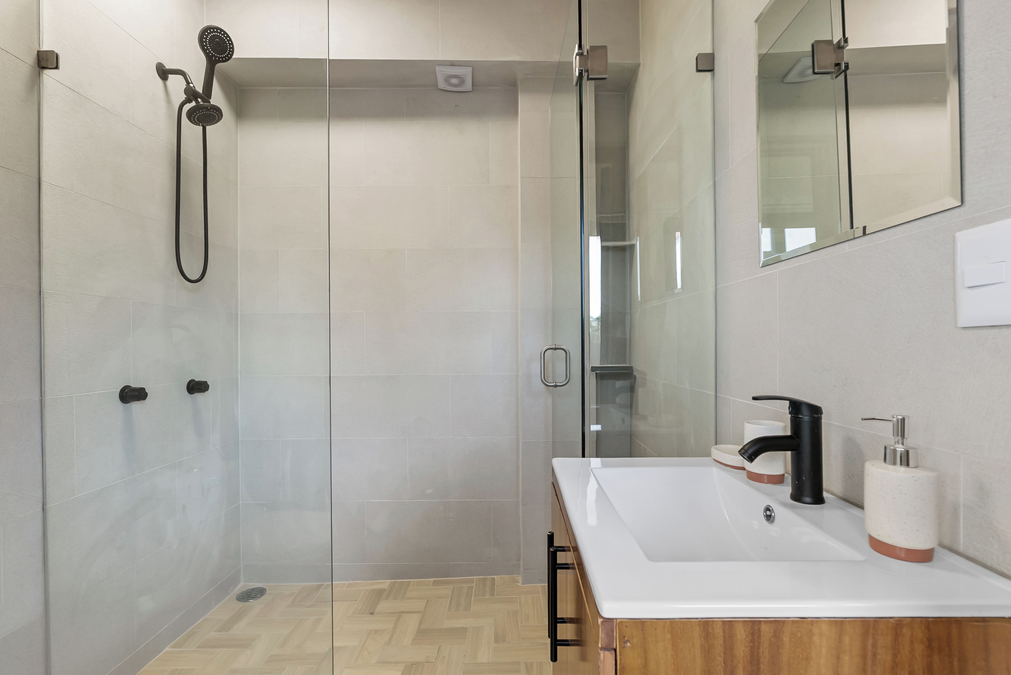 Un baño moderno con ducha, lavamanos y espejo.