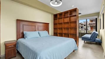 Un dormitorio con cama de madera, mesita de noche, estantería empotrada de madera y vistas al exterior a través de un ventanal grande.
