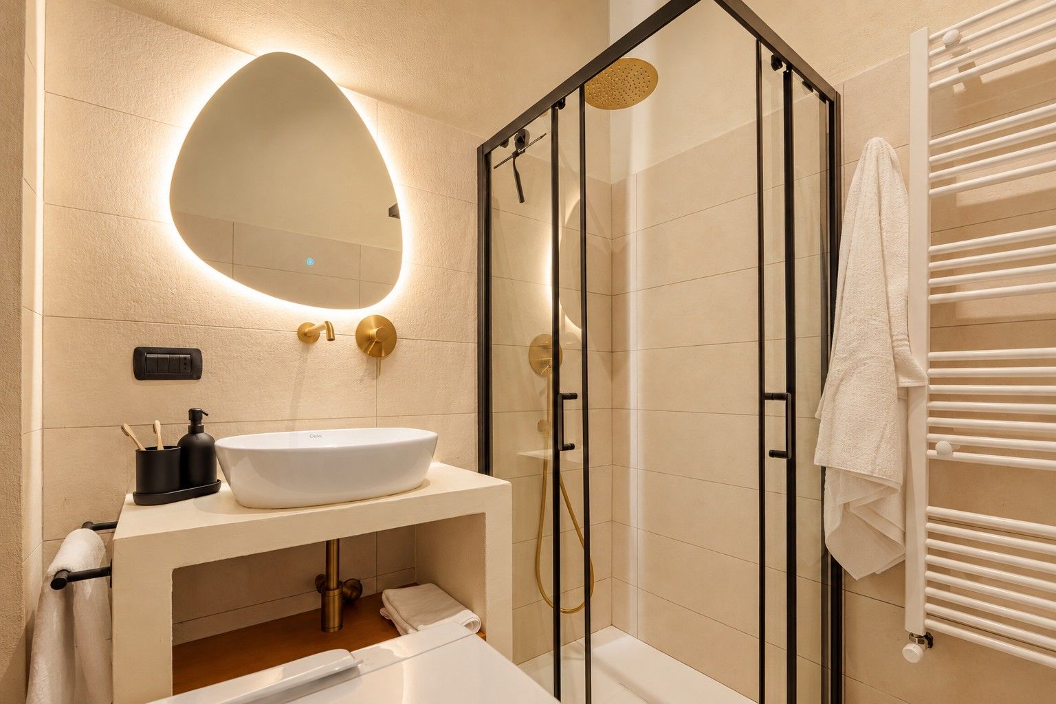 Un baño moderno con ducha envuelta en vidrio, un lavamanos blanco y un perchero para toallas.