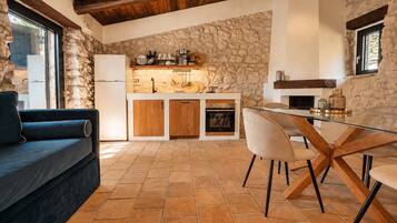 A modern kitchen with stone walls, a built-in oven, and a dining area with a glass table and chairs.