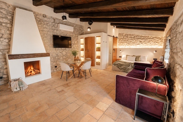 A cozy room with a stone wall, a fireplace, a television, and a comfortable seating area.