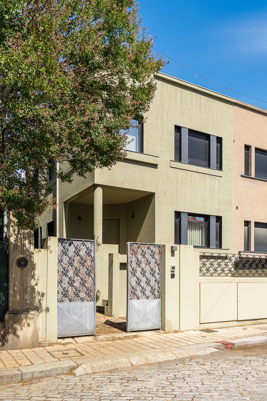 Ein modernes, zweistöckiges Gebäude mit flacher Fassade, einer überdachten Einfahrt und einem befestigten Auffahrtsweg.