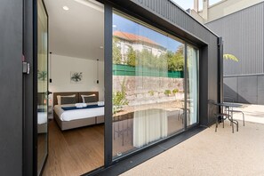 Ein modernes Schlafzimmer mit einer großen Schiebeglasdoor, die auf eine Außenpatio führt.