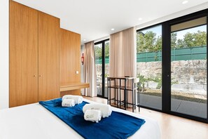 Ein Hotelzimmer mit einem Bett, einem Holzschrank, einem kleinen Tisch und Blick ins Freie.
