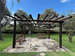 A wooden pergola structure with benches underneath, set in a grassy park area. - Chácara Rockie offers an experience of comfort, elegance, and exclusivity. (Itatiba)