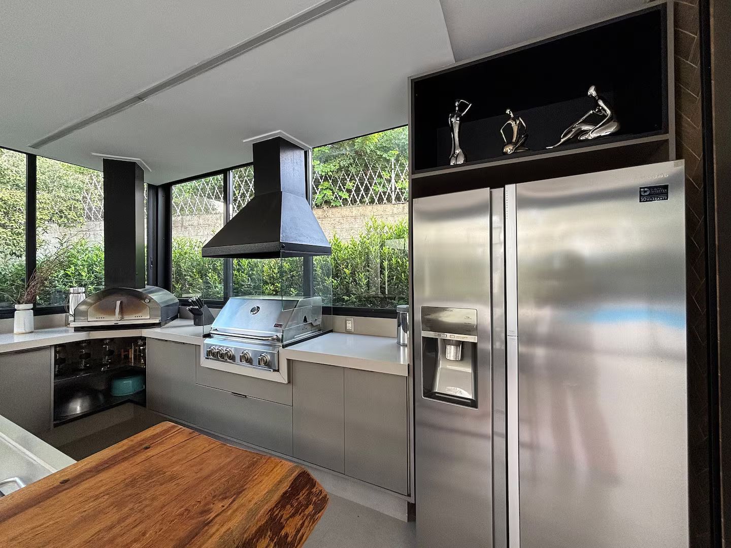 Una cucina moderna con una griglia integrata, un frigorifero in acciaio inossidabile e un'ampia finestra vista sul verde.