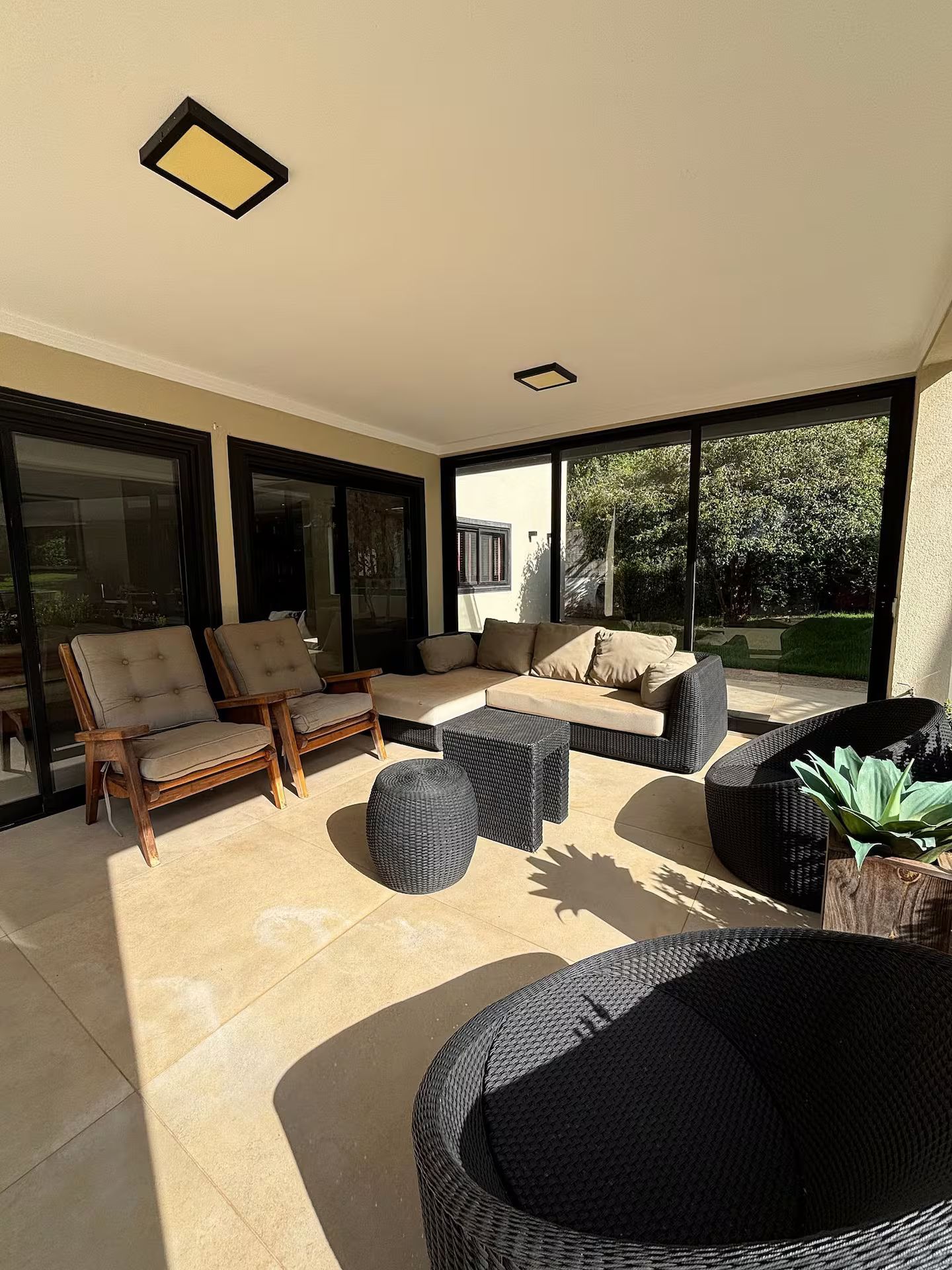 A sunlit outdoor seating area with a sofa, chairs, and a wicker table.