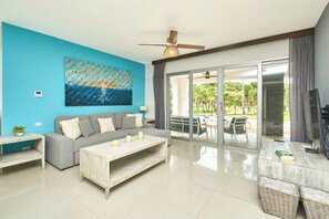 A modern living room with a sofa, coffee table, and a television. - Mareazul luxury condo | Beach & Resort Pools (Playa del Carmen)
