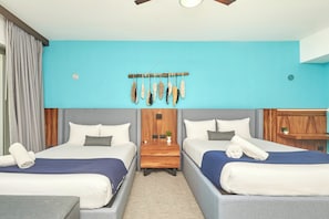 A hotel room with two beds, a wooden headboard, a small table, and a wall-mounted decorative piece. - Mareazul luxury condo | Beach & Resort Pools (Playa del Carmen)