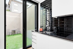 Eine moderne Küche mit schwarzem Fliesenrückwand, einer Edelstahl-Spüle und einem eingebauten Backofen.