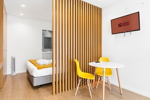 Une chambre d’hôtel avec un lit, une cloison en bois, un écran de télévision et une table avec des chaises.
