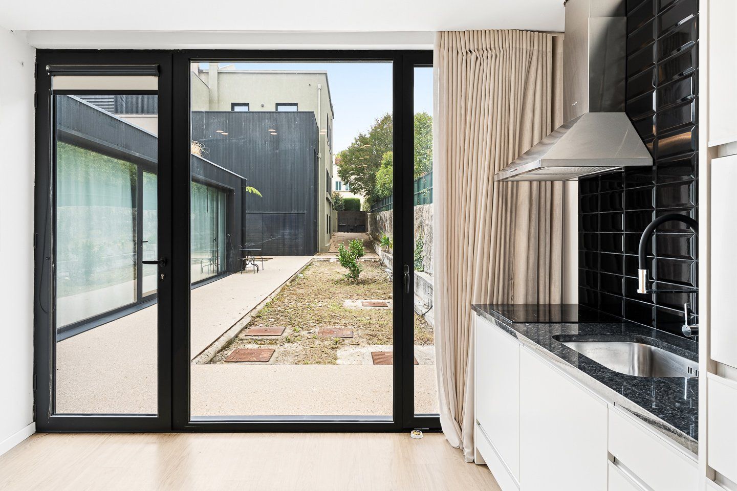Una cuina moderna amb un finestra gran, portes corredisses i vistes cap a l'exterior.