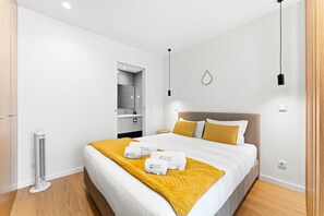 Une chambre d’hôtel comprenant un lit, une table de chevet, un miroir, une lampe fixée au mur et un thermostat.