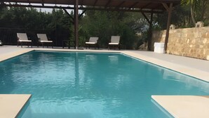 Ein Swimmingpool mit Liegestühlen und einer Obstschale auf der Terrasse.