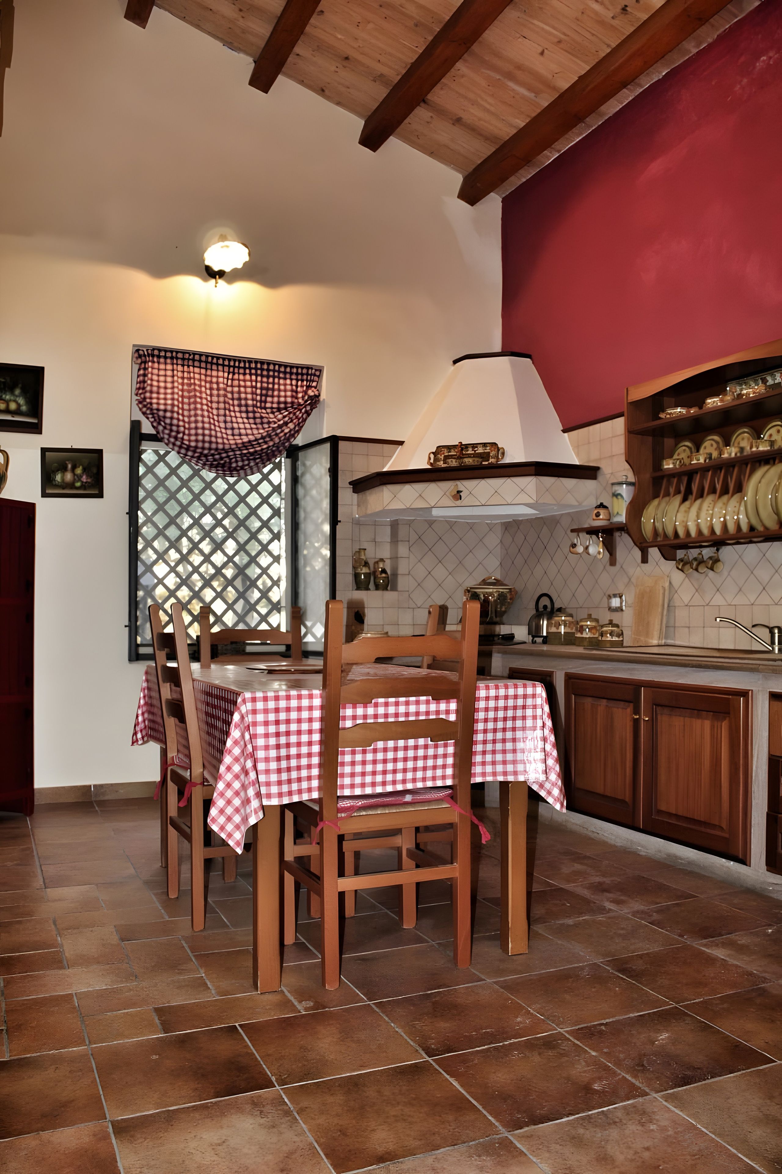 Una cocina con una mesa de comedor preparada para cuatro personas, sillas de madera, un lámpara colgante y un salpicadero de azulejos.