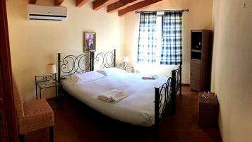 A bedroom with a bed, a bedside table, a lamp, a chair, a wardrobe, and a window with curtains.