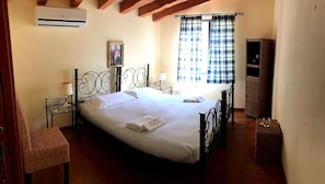 Una camera da letto con un letto, un comodino, una lampada, una sedia, un armadio e una finestra con tende.