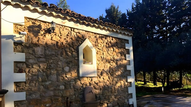 Ein Gebäude aus Stein mit einem Fenster, einem Wasserspeier und einem Ziegeldach.