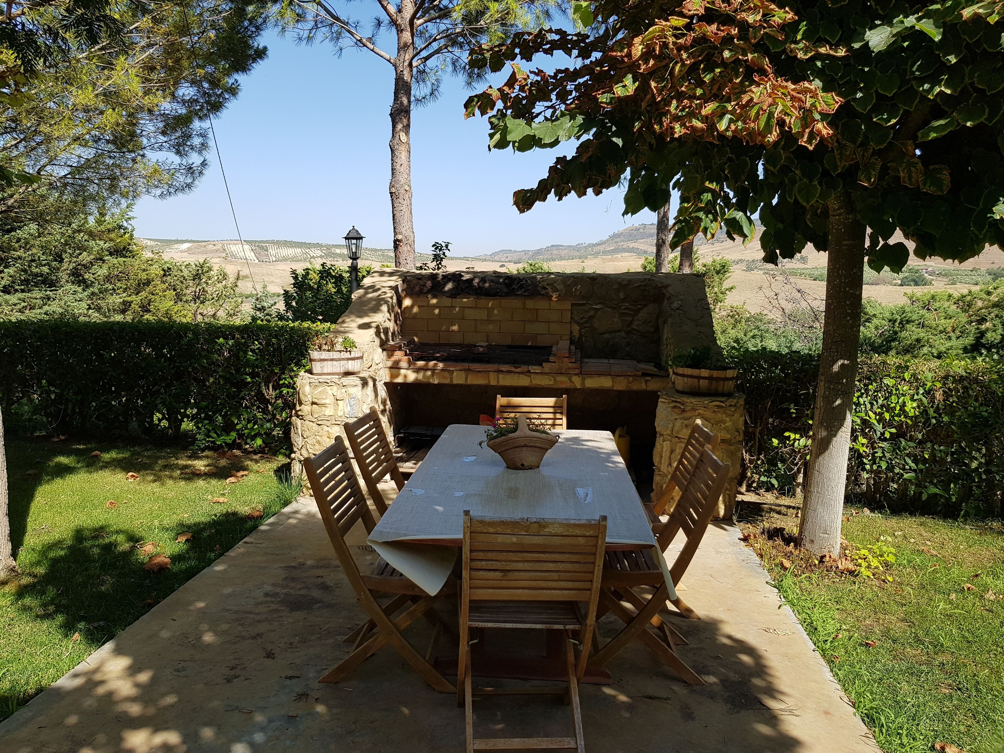 An outdoor dining area with a stone barbecue and a table set for four.