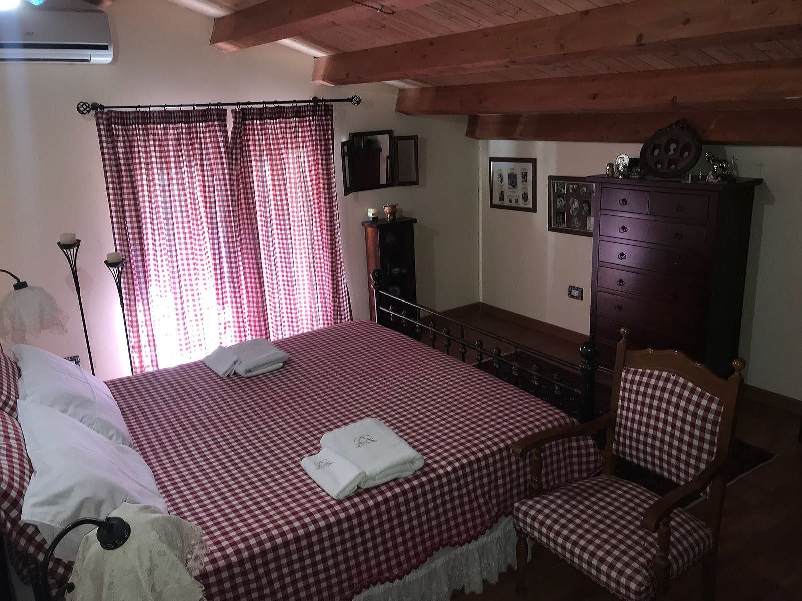 Un dormitorio con colcha a cuadros, una silla de madera, un aparador y un armario.