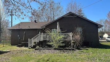 A two-story building with a covered porch and a small staircase.