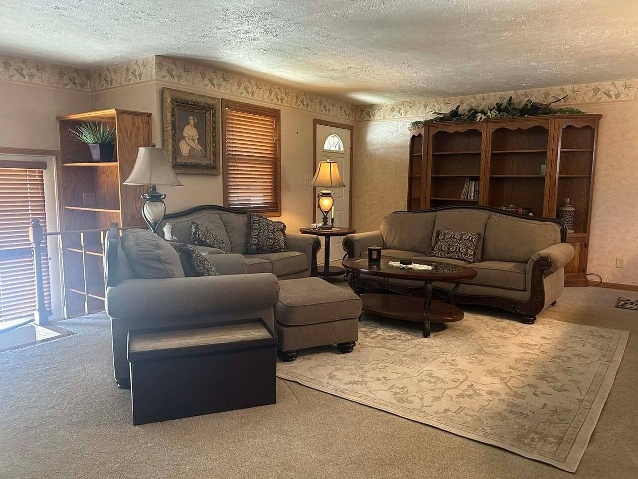 A living room with two sofas, a coffee table, a rug, and a bookshelf.