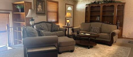 A living room with two sofas, a coffee table, a rug, and a bookshelf.