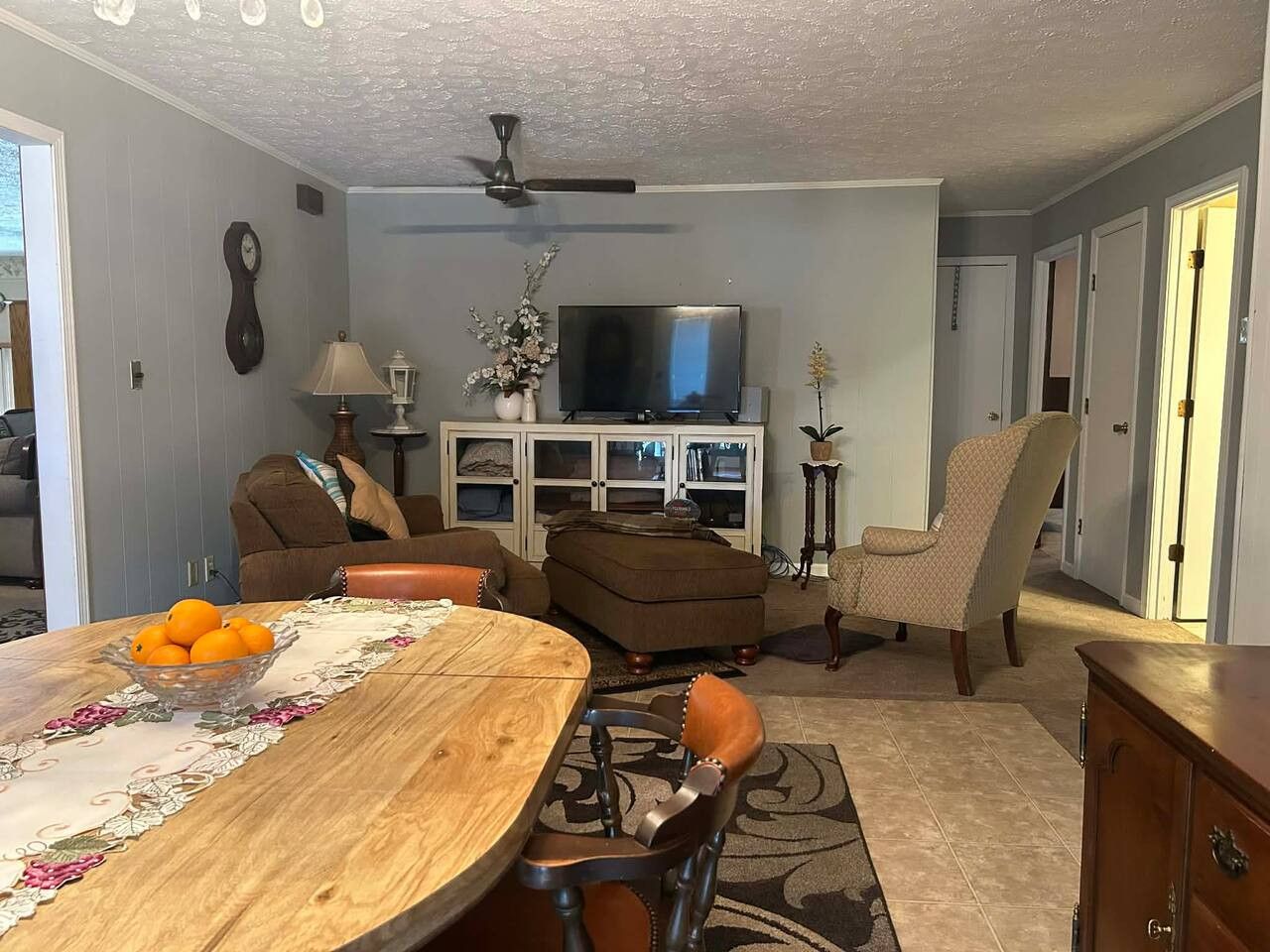 A living room with a dining table, sofas, a television, and a ceiling fan.