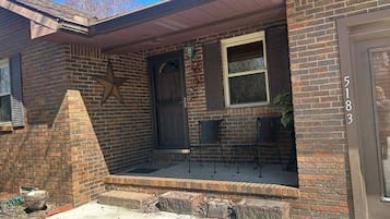 A brick house with a front porch, a star decoration, and a number '5183' on the door.