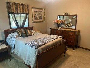 A bedroom with a bed, dresser, mirror, and a framed picture on the wall.