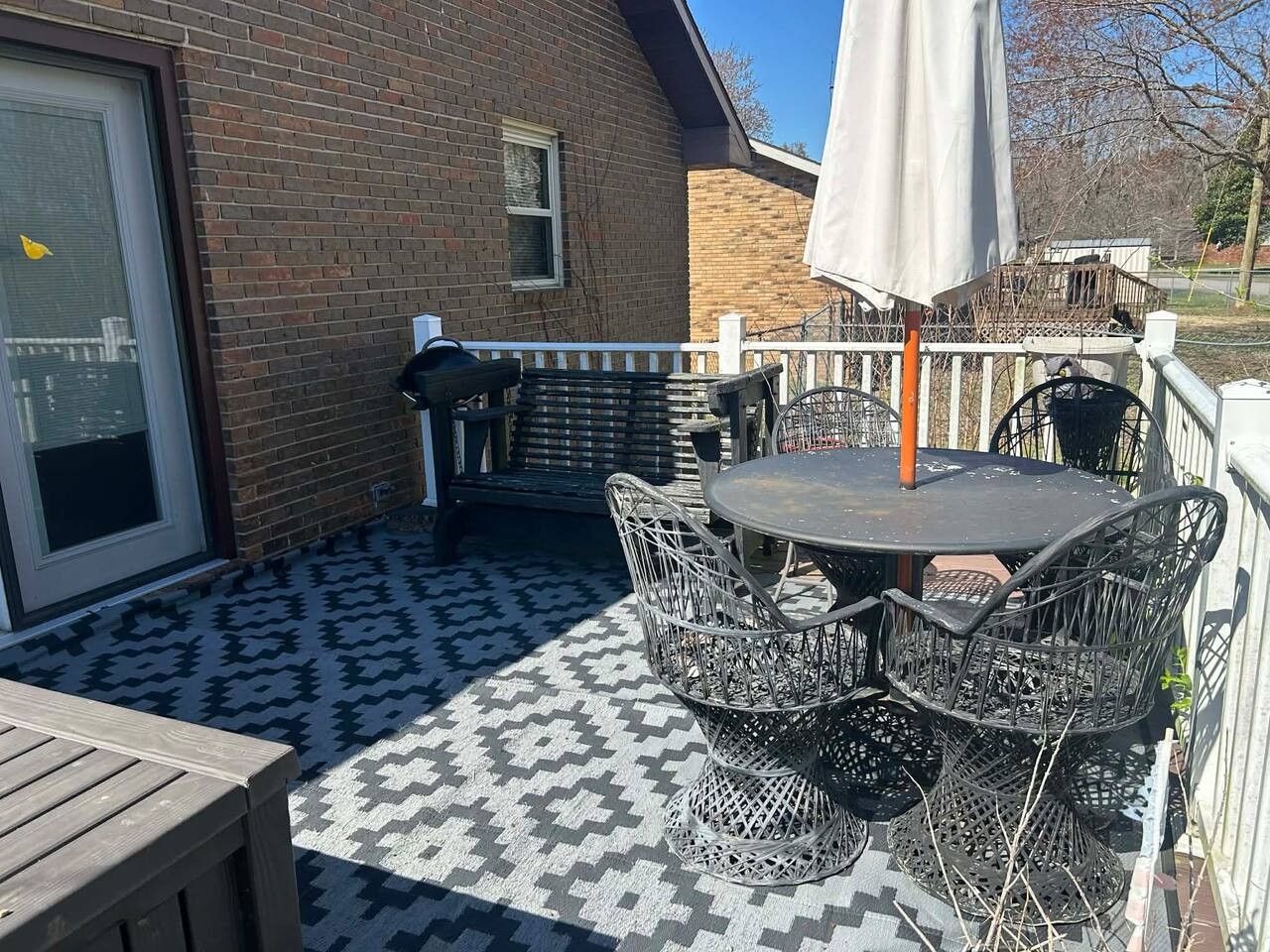 Un patio con piso estampado, una mesa redonda con sillas y una sombrilla.