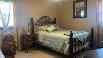 A bedroom with a bed, a nightstand, a desk, and a chair.