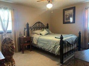 Un dormitorio con cama, mesita de noche, escritorio y silla.