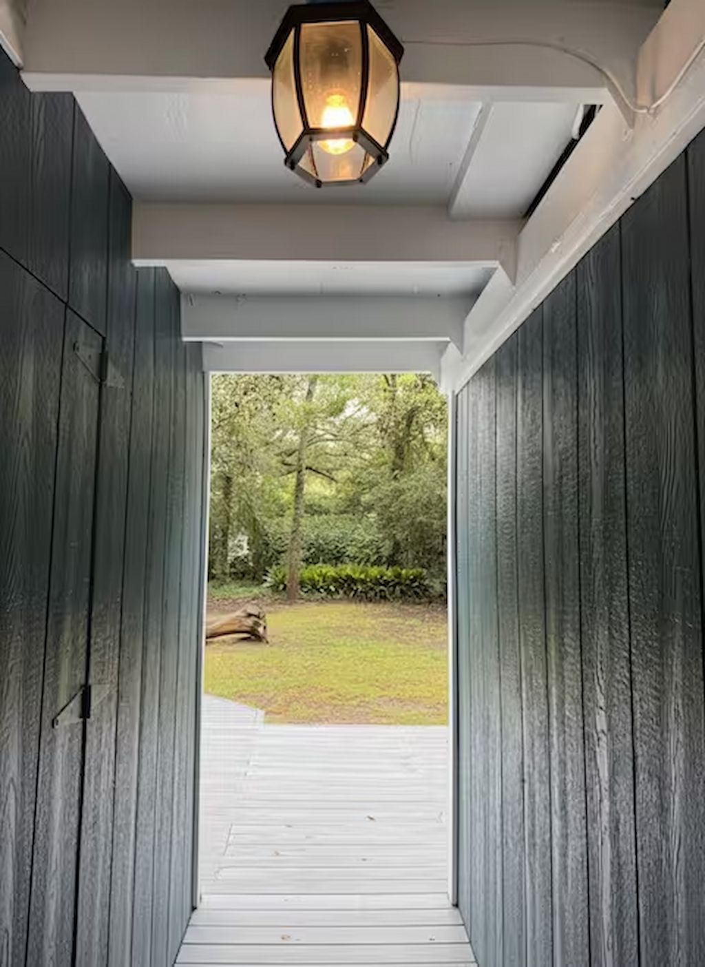A wooden pathway leading to a covered entrance with a lantern overhead.