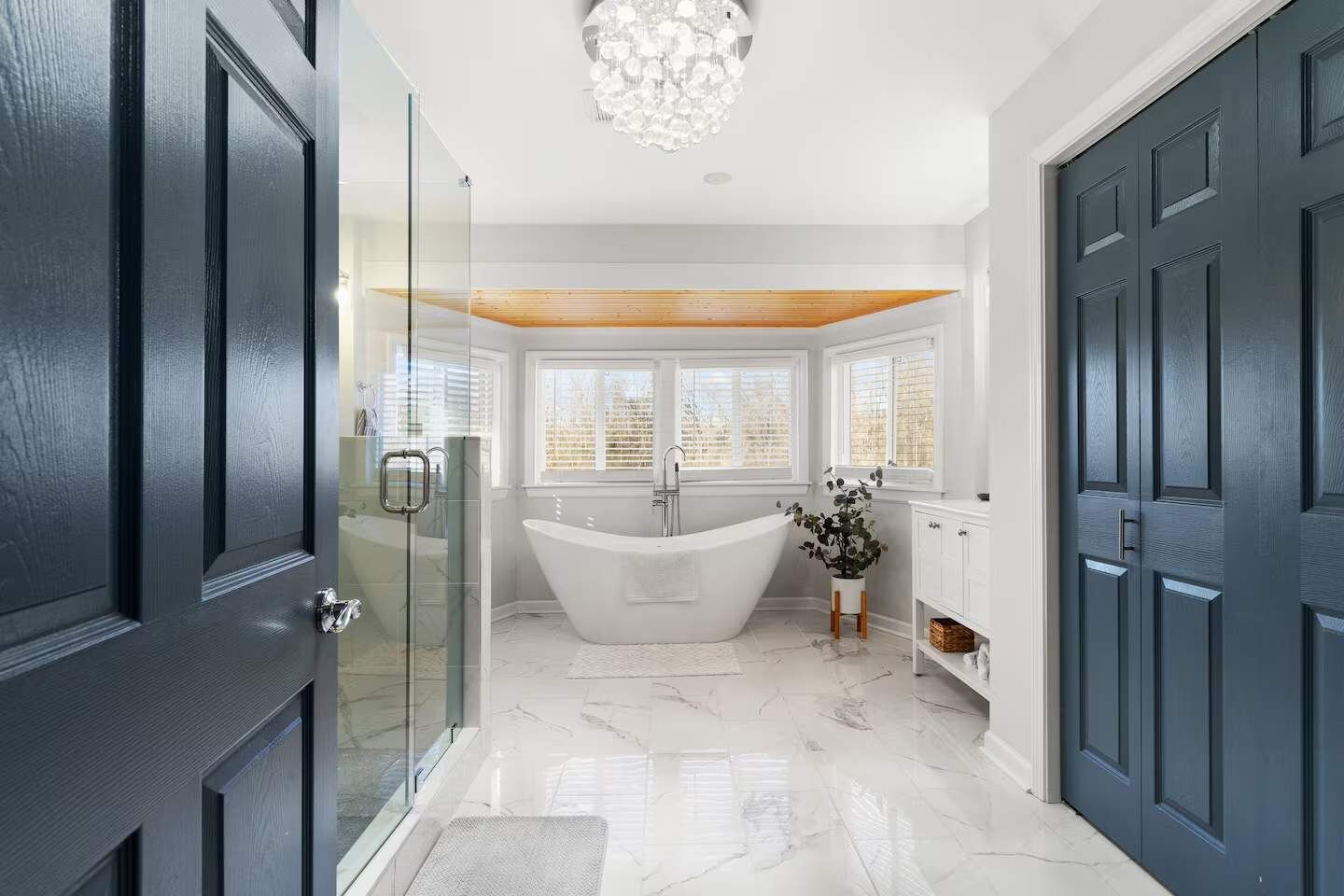 A modern bathroom with a freestanding bathtub, glass shower enclosure, and a wooden ceiling.