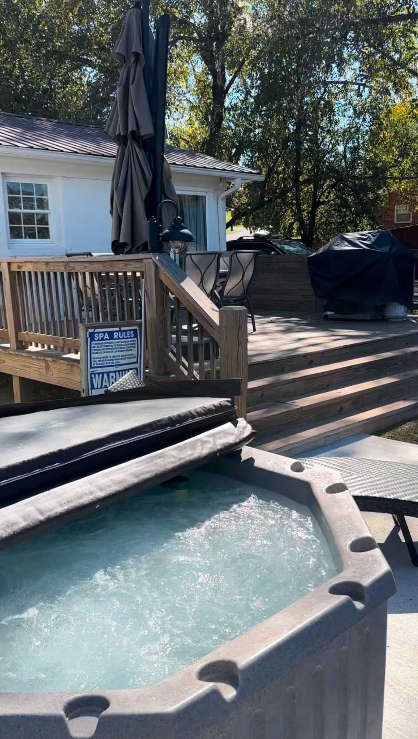 A spa pool area with a wooden deck, a covered seating area, and a sign indicating the pool is a spa.