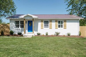 A single-story house with a blue door, white siding, and a small front porch. - *NEW* Shoreline Escape: Lakefront Retreat w/ Hot Tub (Winchester)
