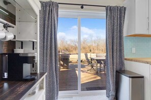 A kitchen with a coffee machine, a sink, and a window with curtains.
