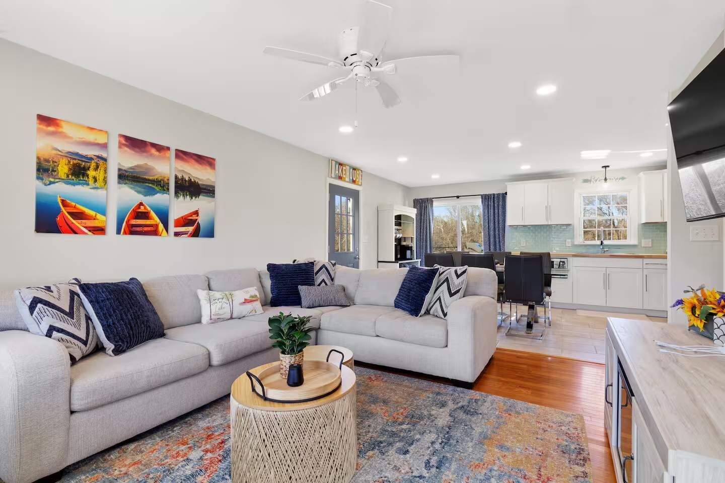 A modern living room with a grey sofa, a round coffee table, and a ceiling fan.