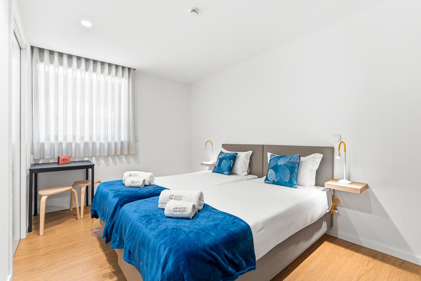 A hotel room with a bed, two bedside tables, a desk, and a chair.