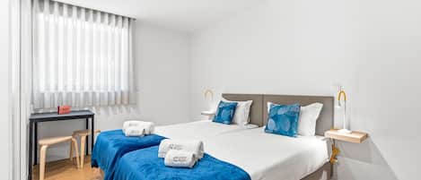 A hotel room with a bed, two bedside tables, a desk, and a chair.