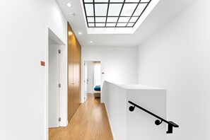 A modern interior with a skylight, wooden flooring, and a white reception desk. - GuestReady - PoetikBlue - Room 1 (Porto)