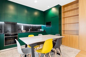 A modern kitchen with green cabinets, a wooden table, and yellow chairs. - GuestReady - PoetikBlue - Room 1 (Porto)
