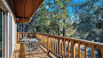 A wooden deck with a table and chairs, surrounded by trees.
