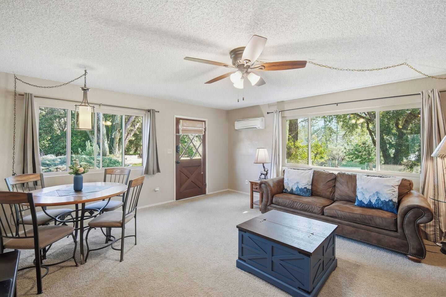 A living room with a dining table, chairs, a sofa, a coffee table, and a ceiling fan.