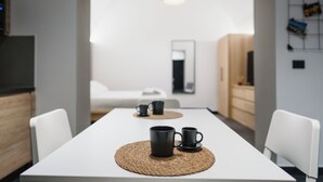 A modern, minimalist dining area with a white table, two black mugs, and a woven placemat. - Harry's House Trani (Trani)